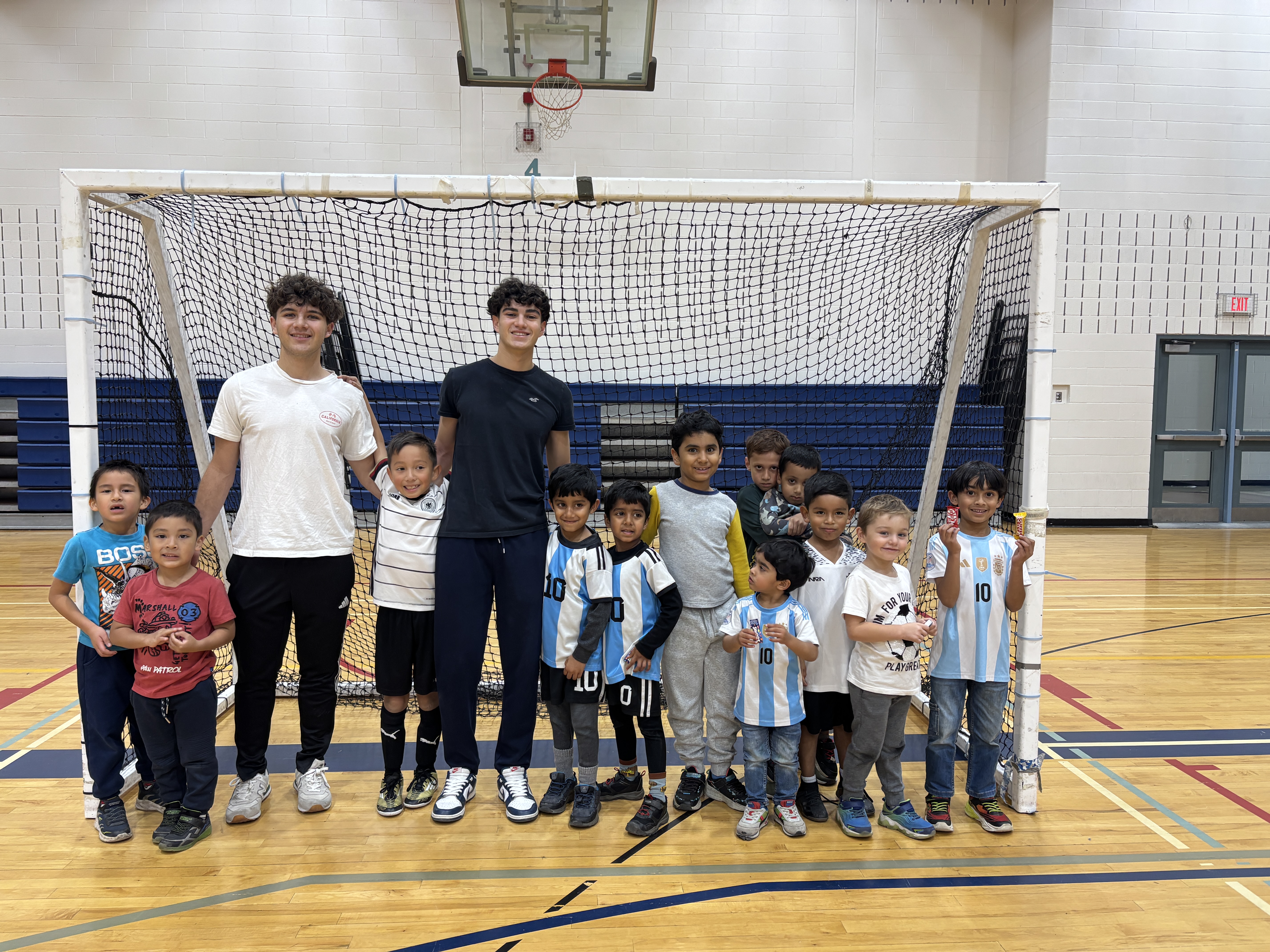 Footy Friends coaches and children gathered in front of a soccer net